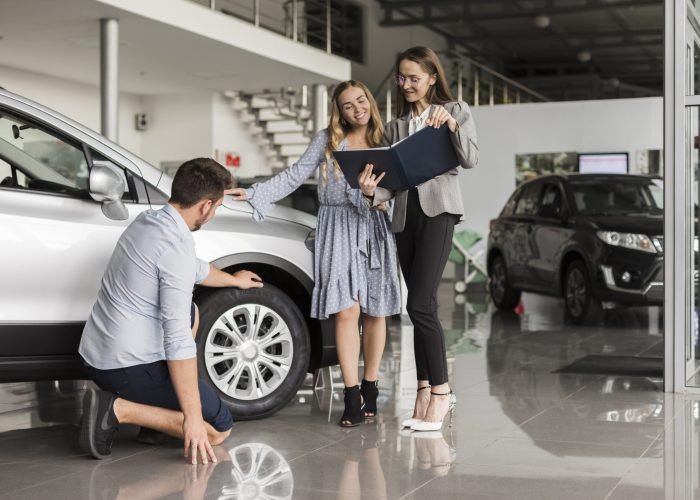 hombre-comprobando-los-neumaticos-del-coche-en-un-showroom hombre-comprobando-los-neumaticos-del-coche-en-un-showroom