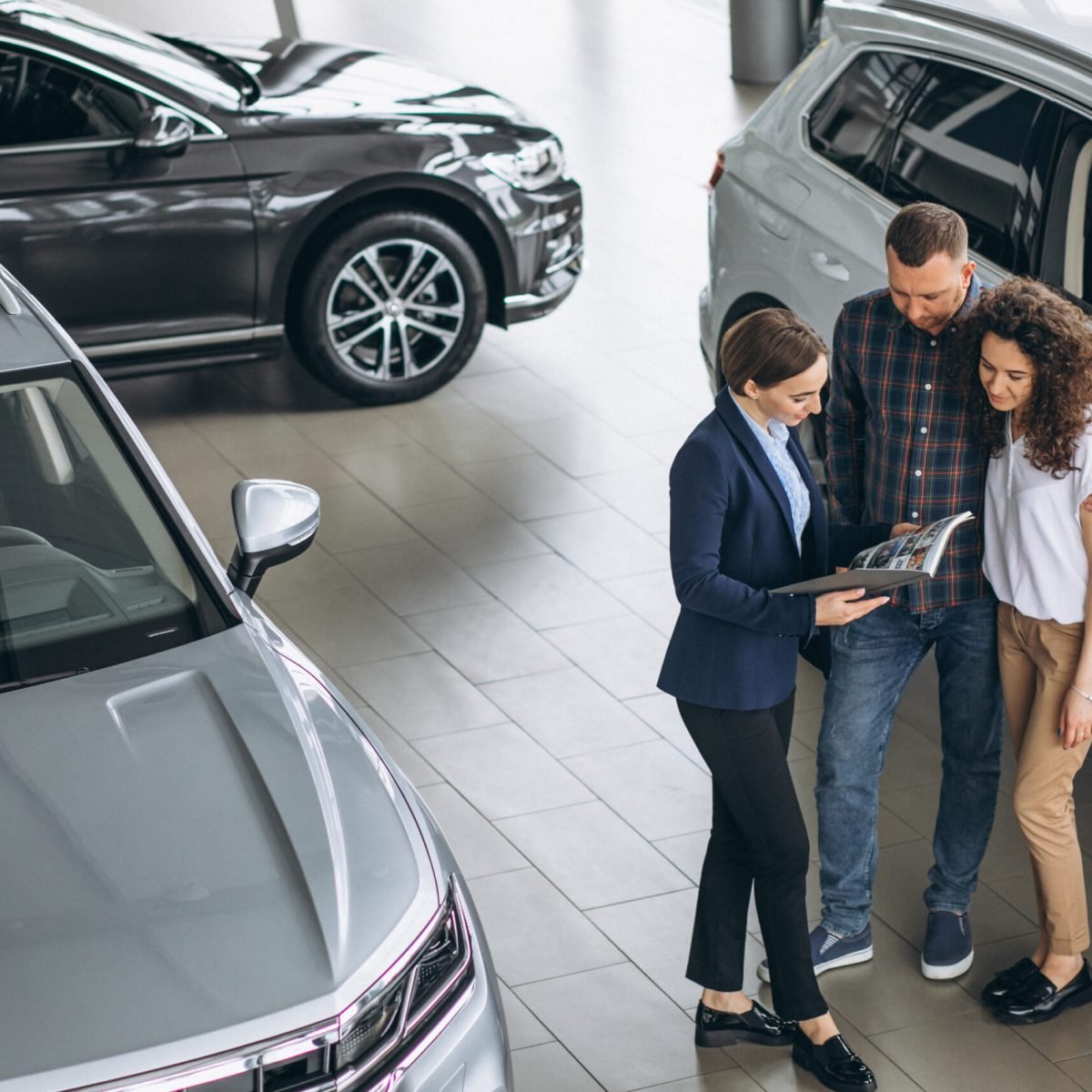 Young couple talking to a sales person in a car showroom Young couple talking to a sales person in a car showroom